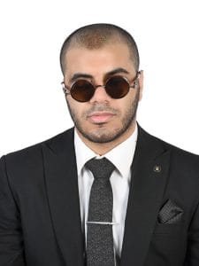 Professional headshot of Abdallah Ashraf, a Translator, Marketer, and Accessibility Advocate, wearing a formal black suit and round sunglasses