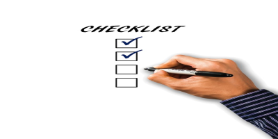 A hand holding a pen and checking boxes on a written checklist